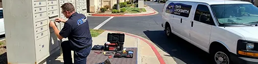 Tim's Locksmith Service technician servicing a commercial mailbox lock unit at a property in Carlsbad, California. Master key systems, access control, panic bars, and business locksmith solutions across San Diego County.
